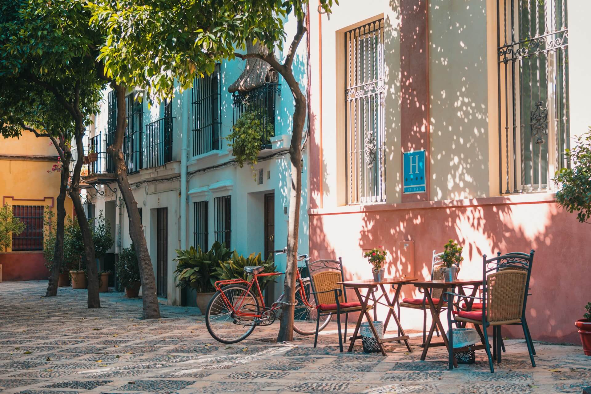 Trees, tables, chairs, bike on Sevilla street.